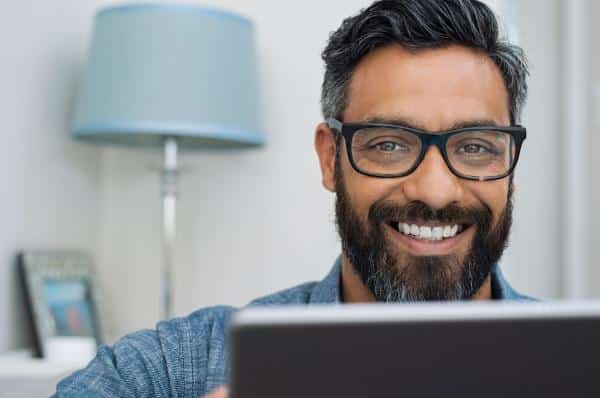 Man smiling from behind computer monitor