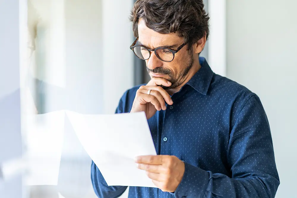 Business man wearing glasses holding paper document.