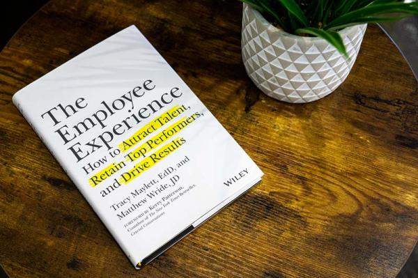 Photo of The Employee Experience Book sitting on a desk near a plant