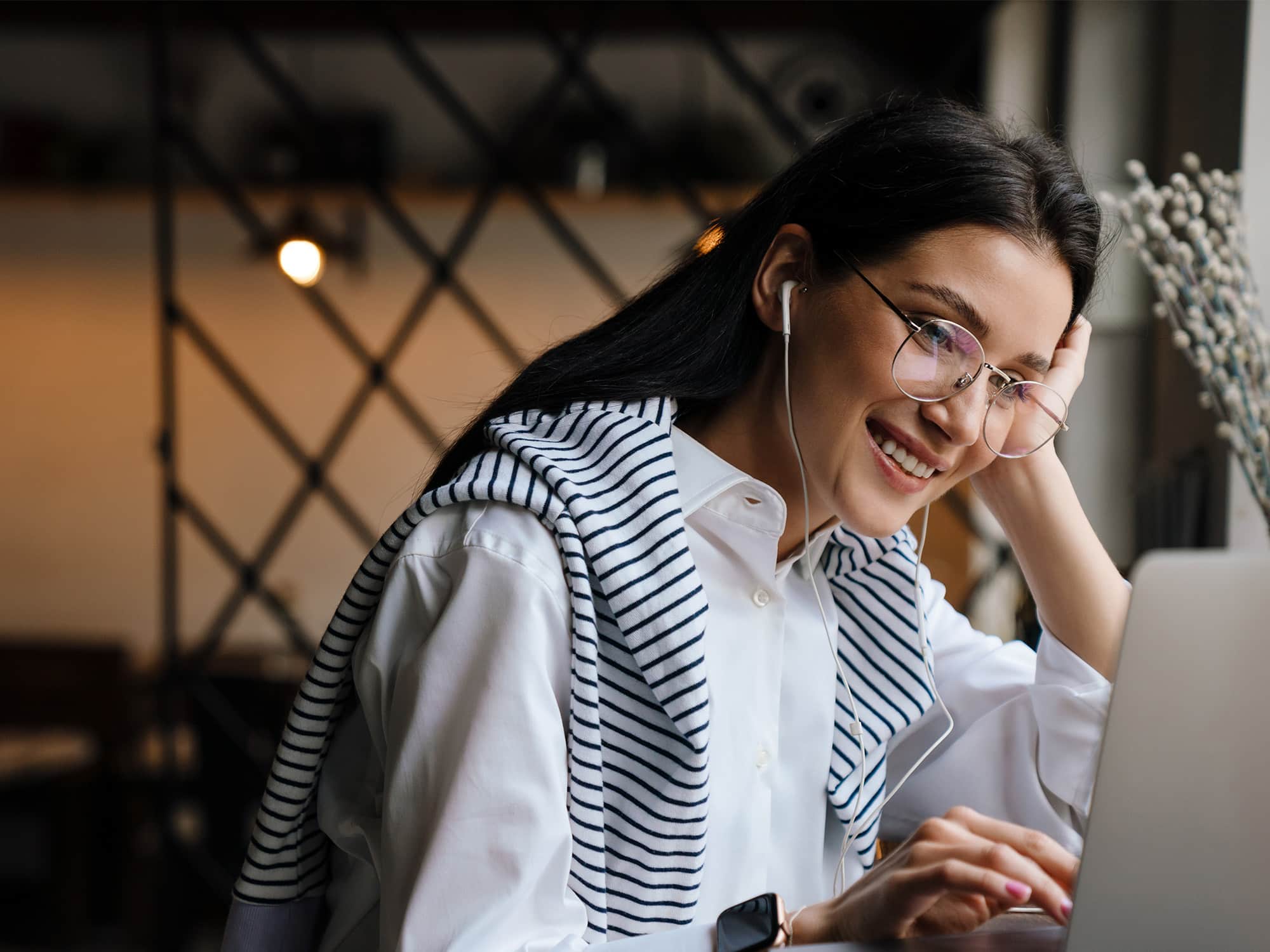 Woman smiling, looking at computer screen with her headphones in