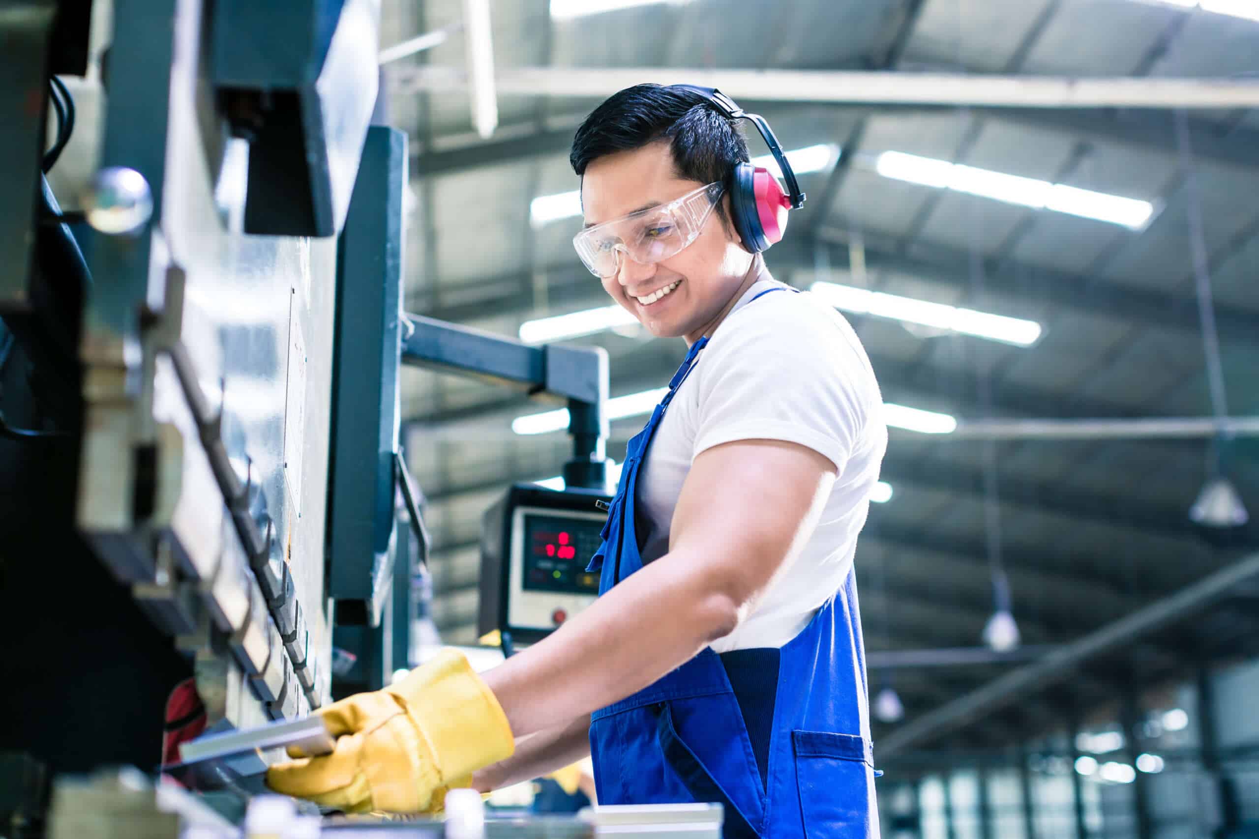 A engaged employee at a manufacturing plant works with machinery.